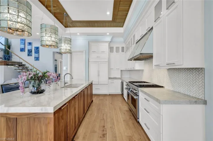 Kitchen with glass insert cabinets, dual tone cabinetry, double oven range, hanging light fixtures, and light wood-type flooring