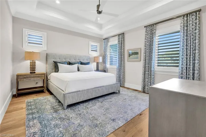 Bedroom with light wood-style floors, a ceiling fan, multiple windows, and recessed lighting