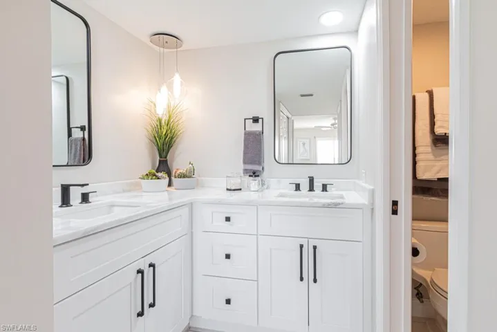 Master bath vanity with 2 sinks, granite countertop, pendant light, and stylish mirrors.