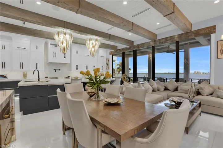 Dining space with beam ceiling, a water view, a chandelier, and recessed lighting - Virtually Edited Image