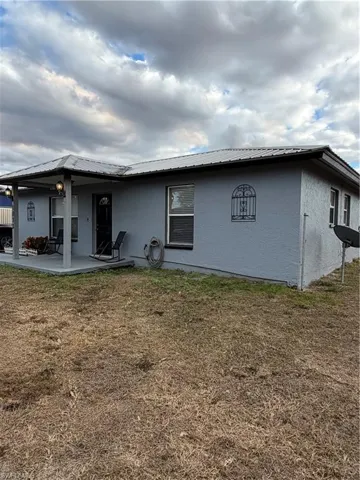 Back of property with a metal roof, a yard, and stucco siding