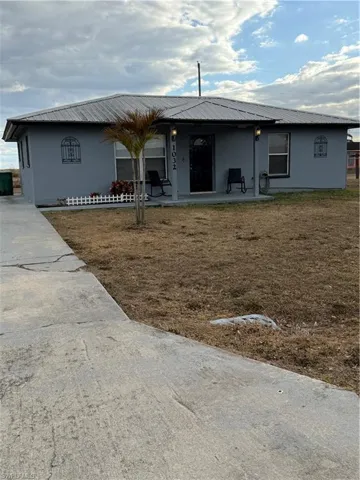 Rear view of house featuring a metal roof, a patio, and a lawn