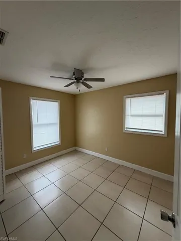 Spare room featuring ceiling fan, light tile patterned floors, and plenty of natural light