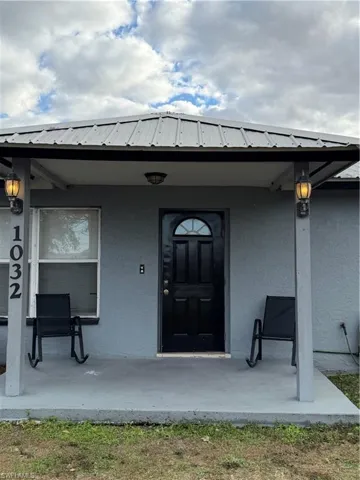 Entrance to property featuring stucco siding, a metal roof, and a porch