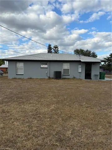 Back of house featuring a metal roof, a yard, and stucco siding