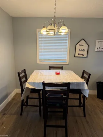Dining area featuring suspended lighting and dark wood-type flooring