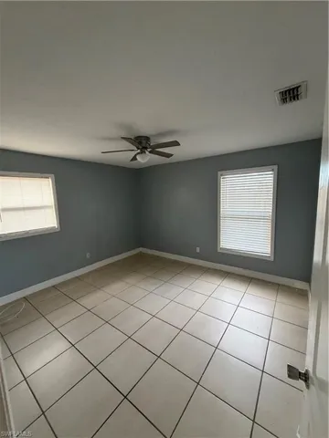 Empty room featuring ceiling fan and light tile patterned floors