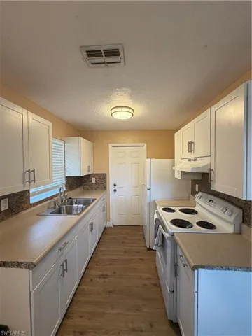 Kitchen with range, white cabinets, dark wood-style flooring, extractor fan, and a textured ceiling