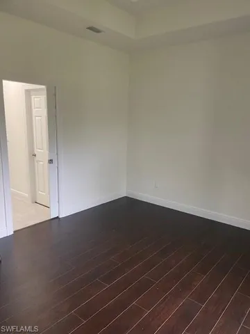 Unfurnished room with dark wood finished floors and a tray ceiling