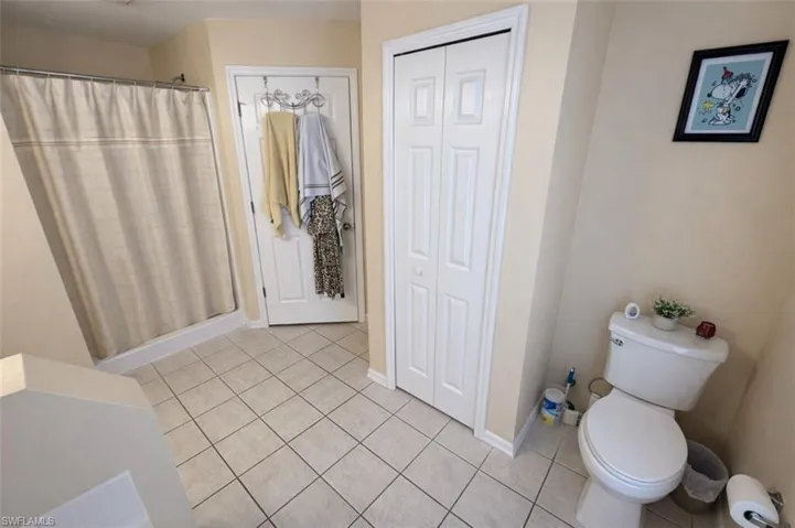 Bathroom featuring a closet, a shower stall, and light tile patterned floors