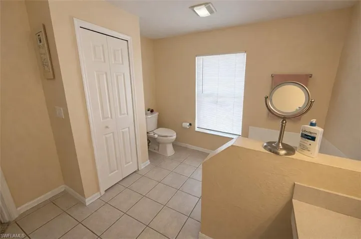Bathroom featuring a closet, light tile patterned flooring, and vanity