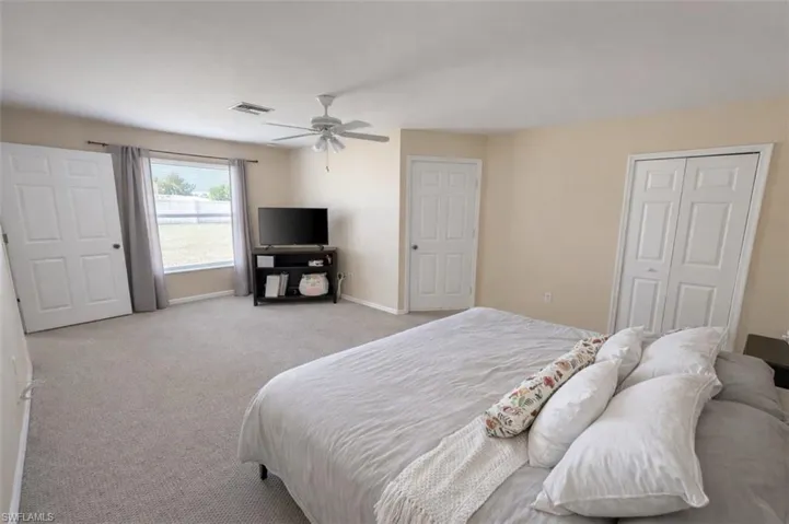 Carpeted bedroom with a ceiling fan and a closet