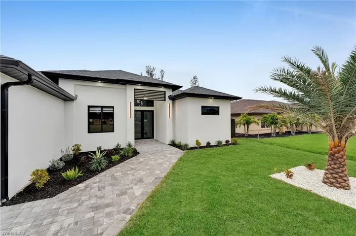 View of front of property with a shingled roof, a front lawn, and stucco siding