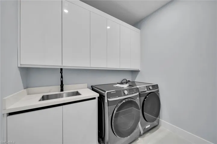 Washroom with separate washer and dryer, a sink, cabinet space, and baseboards
