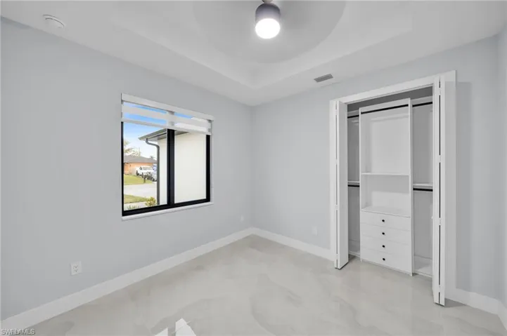 Unfurnished bedroom featuring a ceiling fan, a tray ceiling, visible vents, and baseboards