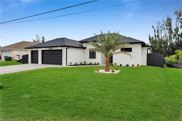 View of front of property featuring decorative driveway, stucco siding, an attached garage, a front yard, and fence