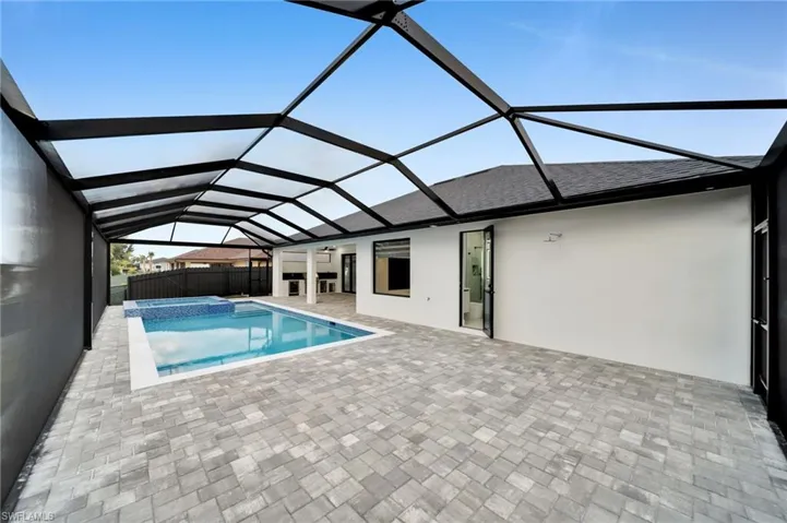 View of pool with a pool with connected hot tub, a patio area, fence, and a lanai