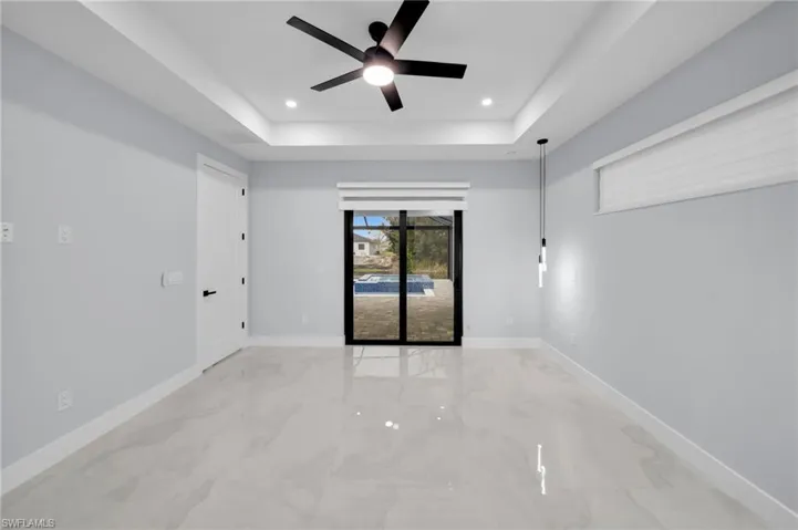 Spare room featuring marble finish floor, a tray ceiling, recessed lighting, and baseboards