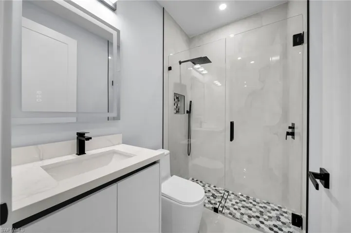 Bathroom with vanity, a marble finish shower, and toilet