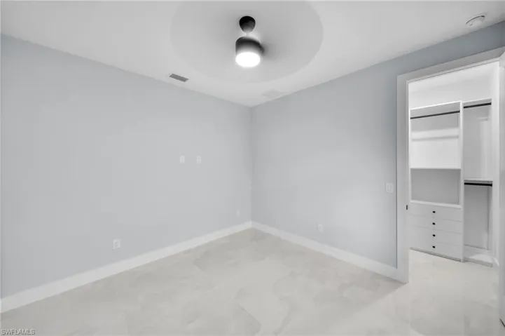 Unfurnished bedroom with baseboards, visible vents, a ceiling fan, a walk in closet, and a closet