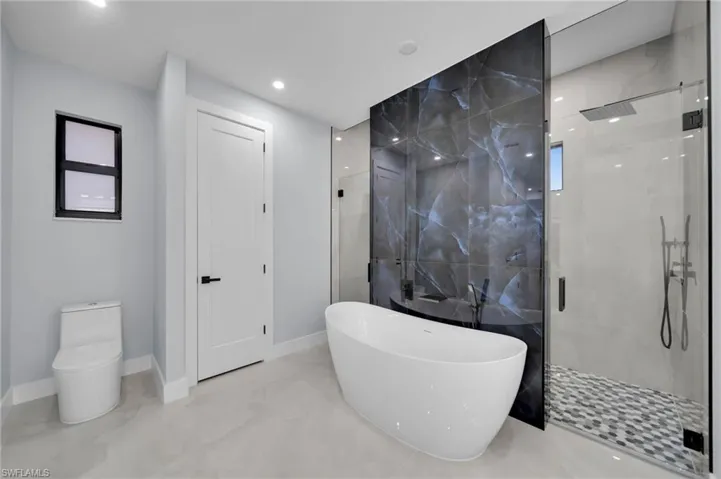 Full bathroom featuring toilet, a soaking tub, marble finish floor, a shower stall, and recessed lighting