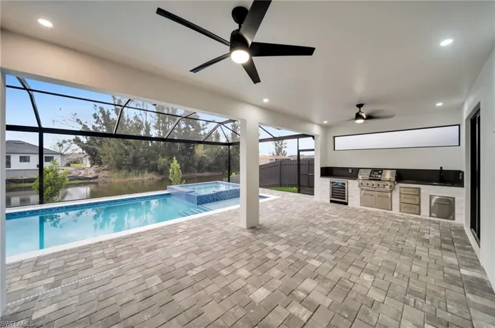 View of swimming pool with a patio area, an outdoor kitchen, a lanai, and a ceiling fan