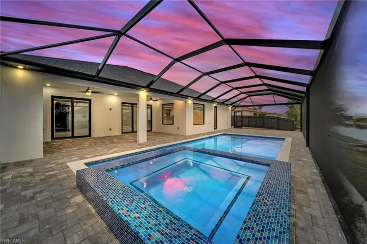 View of swimming pool with a patio area, ceiling fan, fence, an in ground hot tub, and a lanai