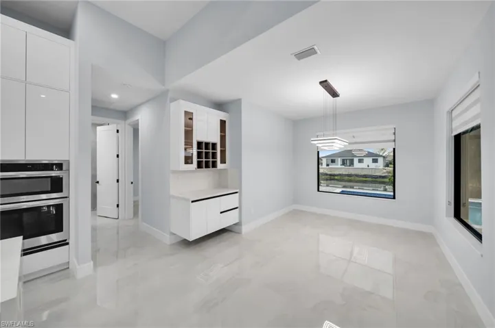 Kitchen with visible vents, glass insert cabinets, stainless steel double oven, white cabinetry, and modern cabinets
