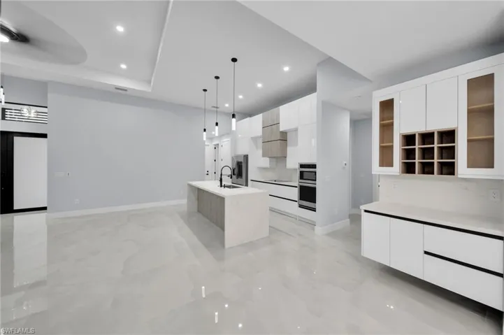 Kitchen featuring modern cabinets, a center island with sink, and white cabinetry