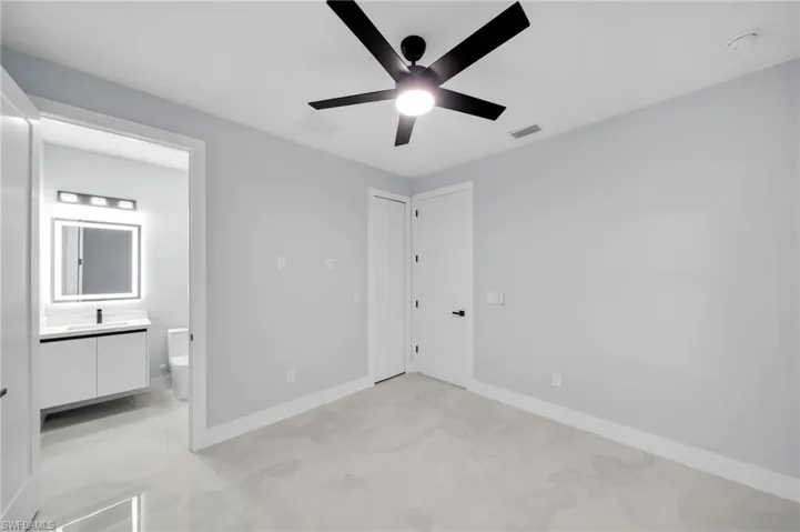 Unfurnished bedroom featuring a ceiling fan, ensuite bath, visible vents, and baseboards