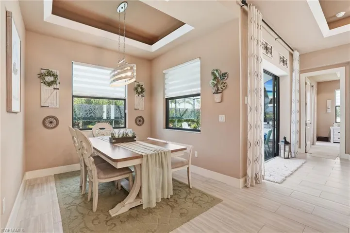 Dining area with a tray ceiling and light wood finished floors