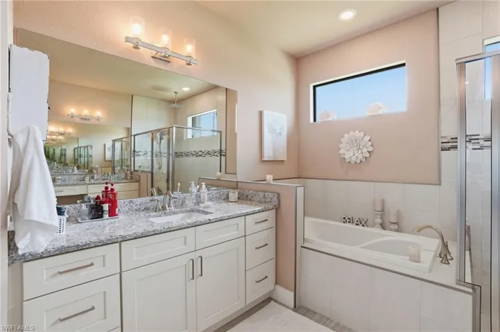 Full bath with a shower stall, vanity, healthy amount of natural light, a bath, and recessed lighting
