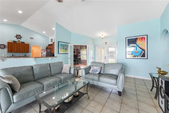 Living room with french doors, light tile patterned flooring, and lofted ceiling