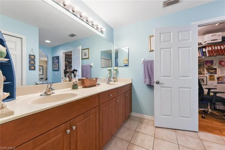 Bathroom with a spacious closet, light tile patterned floors, and double vanity