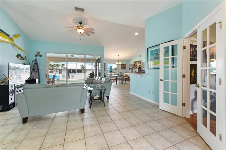 Living area featuring light tile patterned floors, a ceiling fan, vaulted ceiling, a chandelier, and recessed lighting