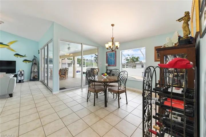 Dining space with light tile patterned flooring, lofted ceiling, and a chandelier