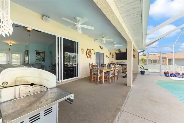 View of patio with a sunroom, glass enclosure, a ceiling fan, an outdoor pool, and outdoor dining space