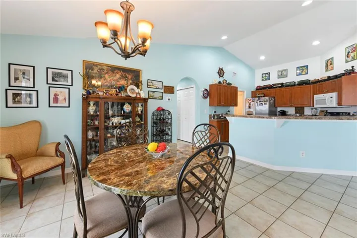 Dining space featuring lofted ceiling, arched walkways, light tile patterned floors, a chandelier, and recessed lighting