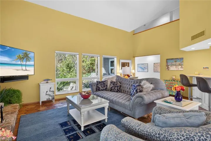 Tiled living room with high vaulted ceiling and baseboards