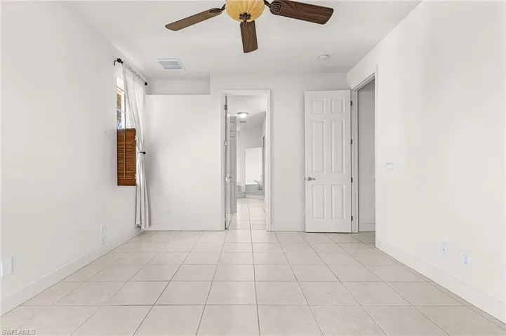 Unfurnished bedroom with ceiling fan, connected bathroom, and light tile patterned floors