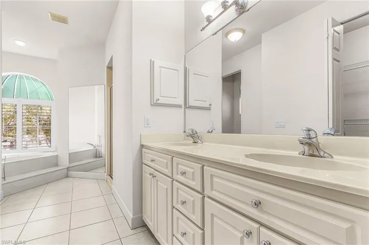 Bathroom featuring a bath, double vanity, light tile patterned floors, and a stall shower