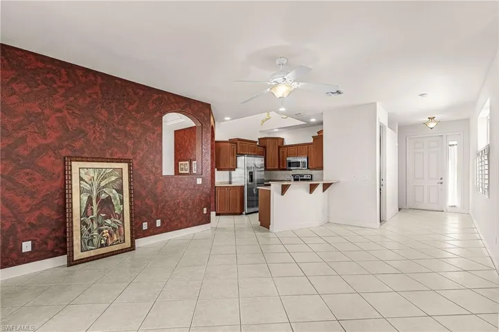 Kitchen with a breakfast bar, brown cabinets, light tile patterned flooring, a peninsula, and light countertops
