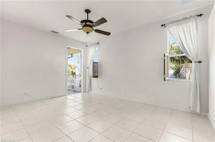 Empty room with healthy amount of natural light, a ceiling fan, and light tile patterned floors