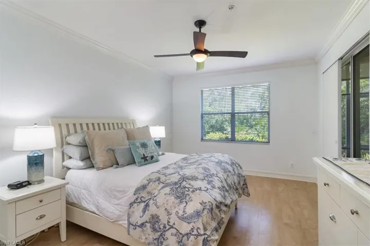 Bedroom with light hardwood / wood-style floors, crown molding, and ceiling fan