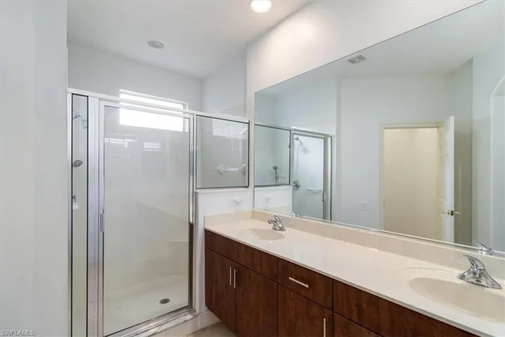 Bathroom with an enclosed shower, large vanity, and double sink