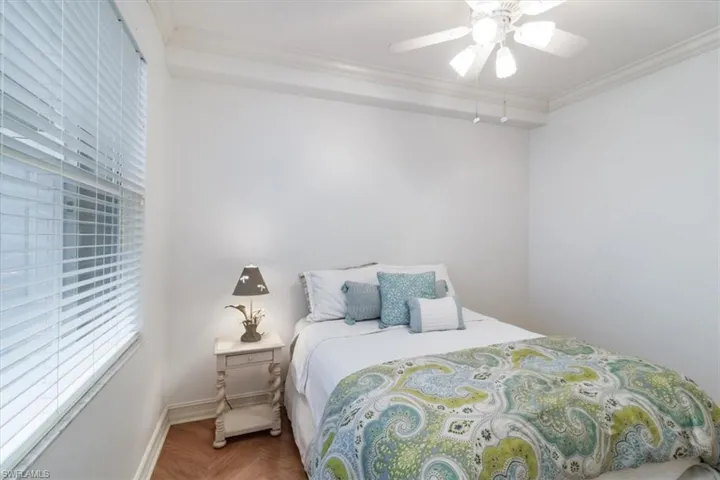 Bedroom with parquet flooring, ceiling fan, and crown molding