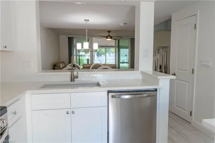 Kitchen featuring appliances with stainless steel finishes, white cabinetry, a ceiling fan, light stone counters, and open floor plan