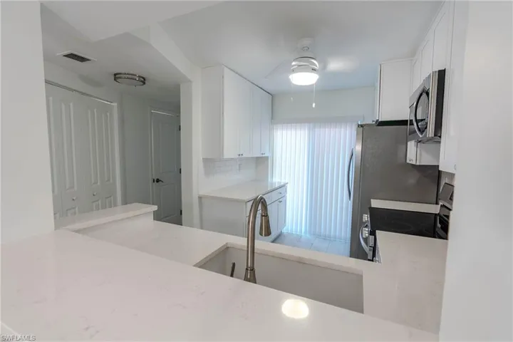 Kitchen with white cabinets, stainless steel microwave, electric stove, a ceiling fan, and tasteful backsplash