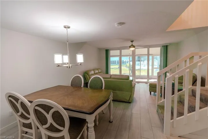 Dining area featuring stairway, a wall of windows, light wood-style flooring, and a ceiling fan