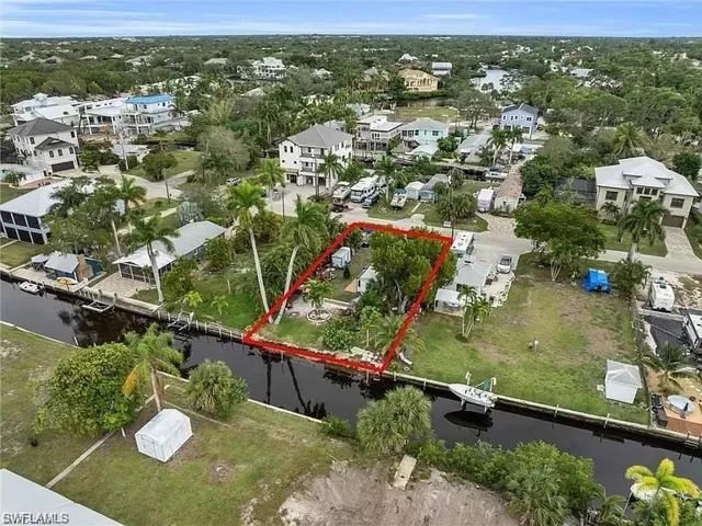 Aerial perspective of suburban area featuring property boundaries highlighted and a nearby body of water